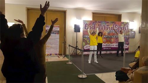 '图：法轮功学员还在展示舞台那里每天定时为过往民众介绍和演示法轮功修炼方法，很多民众开始学炼'