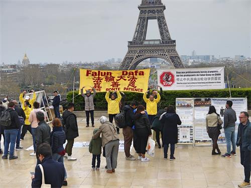 '图1：三月二十四日下午，人权广场人流不断，法轮功学员在巴黎的人权广场进行炼功和讲真相的活动。人们被法轮功学员安静、祥和的炼功吸引，不少游客驻足了解真相。'