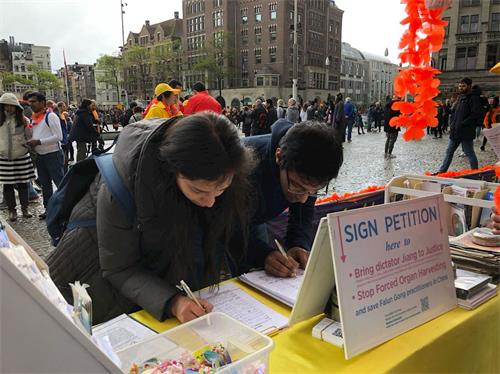 '图3～4： 在首都阿姆斯特丹（Amsterdam）市中心――达姆（Dam）广场上，游客签名支持法轮功反迫害。'
