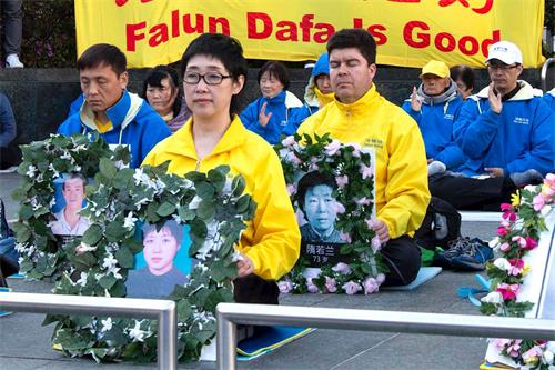 '圖7：今年四月二十日，法輪功學員王易非手持被迫害致死的妹妹王可非的遺像'