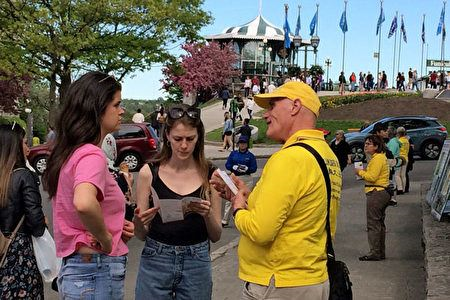 '图18：参加当天活动的魁北克市法轮功学员Alain（图右）一直在广场上和人们交谈，传递法轮大法真相。'