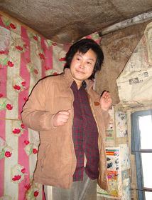 ??年图片：被迫害致疯的柳志梅，当有人试图接近，她就攥着双手躲向自家墙角'