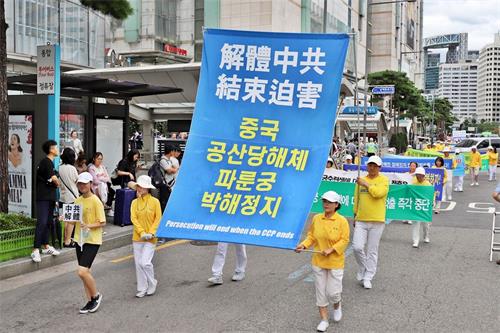 '图24～30：法轮功游行队伍走在首尔乐天百货店前。'