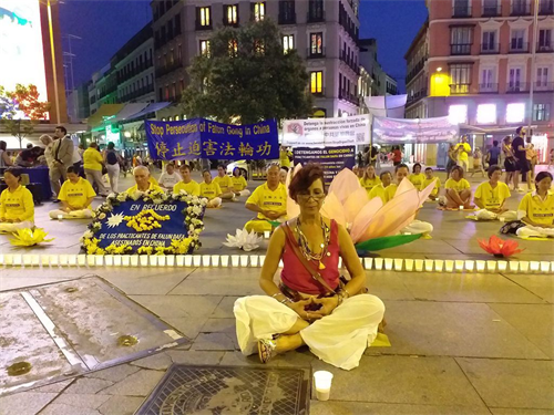 'Figura 3: el 19 de julio de 22019, en la Plaza del Callao de Madrid, la Sra. Vivian Acosta y las practicantes de Falun Gong se sentaron juntas en el suelo y en la vigilia con velas.  '