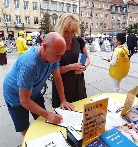 '图16：购买《转法轮》的波兰夫妇在请愿书上签名，反对中共迫害法轮功'