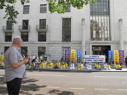 '图1：二零一九年七月二十日，法轮功学员在伦敦中使馆前炼功静坐集会，路人驻足观看。'