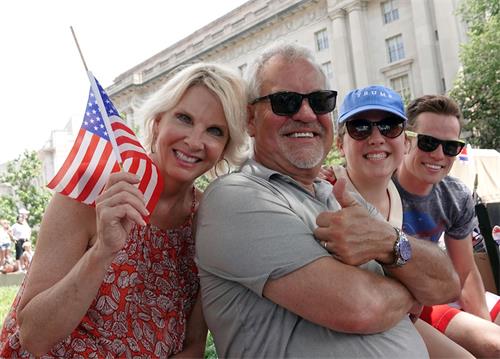 '图8：来自美国新罕布什尔州的马克与太太和两个孩子来华盛顿参加美国独立日庆祝活动，他们第一次看到法轮功学员的游行队伍。'