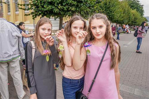 '图8：从左至右：基斯洛沃茨克市年轻人柏丽娜（Polina）索菲亚（Sofia）和 维诺尼雅（ Veronika） 手举和法轮功学员一起折叠的纸莲花'