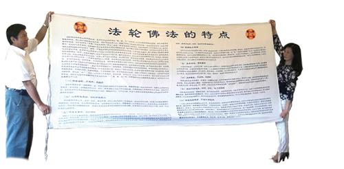 '图3：张震宇与妻子展示保存完好的舅舅一九九五年从贵州带来的“法轮佛法的特点”横幅。（博大出版社提供）'