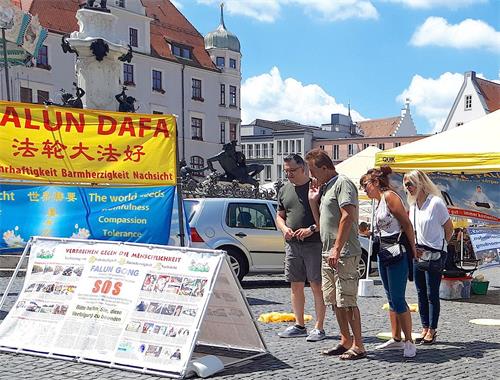 '图1：二零二零年七月十八日，法轮功学员在德国奥格斯堡（Augsburg）的市政厅广场（Rathausplatz）举办信息日活动，吸引了德国民众的关注。'