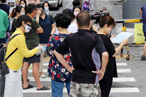 '图24：法轮功学员在韩国首尔街上派发简介，让市民了解真相。'