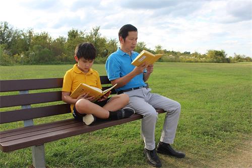 '图2：杨国贤与小儿子一起读《转法轮》书'
