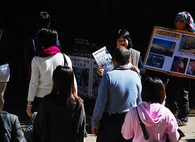 法轮功学员有的拿着展板，有的向中国大陆游客讲真相