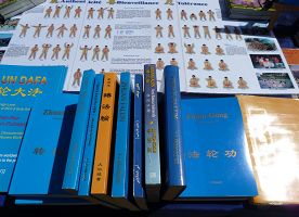 在真相桌上,法轮功学员摆放了被翻译成多种文字的法轮功书籍,及五套功法的介绍。