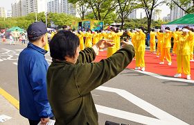 韩国法轮功学员在博士谷艺术节庆典上演示功法，市民也跟着学炼动作