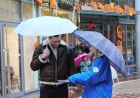 '民众在雨中听法轮功学员讲真相'