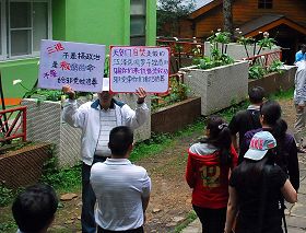 法轮功学员高举看板,揭露天安门自焚造假