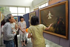 '台湾艺术家黄钜太（左一）聚精会神听解说员介绍画作。'