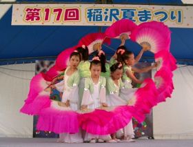明慧学校的法轮大法小弟子在稻泽市第十七届夏季活动节舞台上表演扇子舞