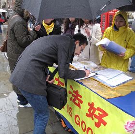'在伦敦圣马丁广场，英国民众在雨中仍踊跃地在给国会议员的请愿信上签名'