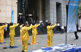 '法轮功学员展示五套功法,人们驻足观看'