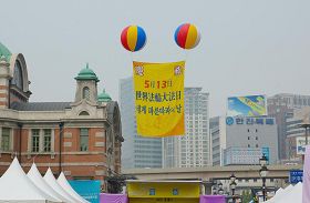 '活动现场首尔站上空飘扬着“庆祝法轮大法洪传21周年”的大型气球'