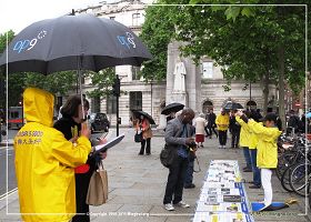 图1、2：二零一三年六月十五日伦敦圣马丁广场：英国法轮功学员在雨中坚持进行讲真相，征签反迫害活动。