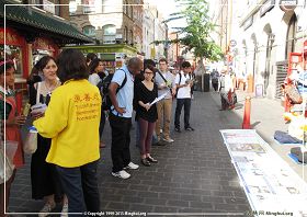 图1：英国法轮功学员在伦敦唐人街演示功法、讲真相并征集支持反迫害的签名，路人纷纷驻足了解真相。