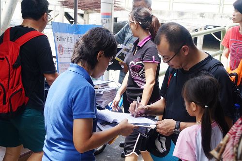 马国吉胆岛村口，当地民众与游客纷纷签名，谴责中共活摘器官暴行。