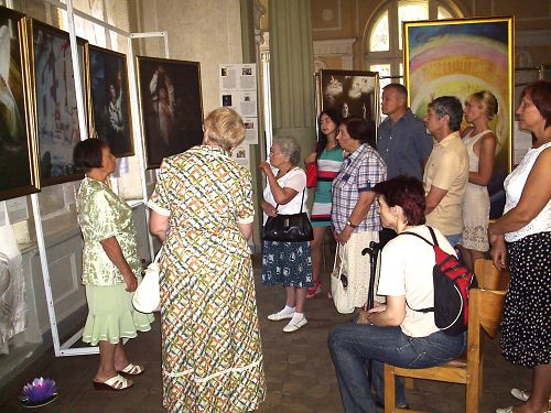 图：乌克兰哈尔科夫市的真善忍美展上，观众欣赏画作，聆听导览。