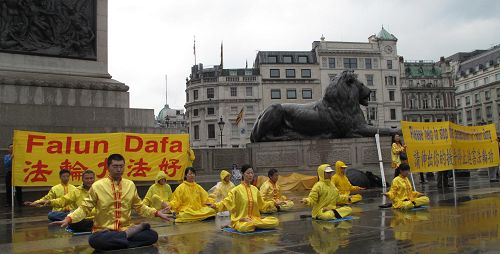 '二零一三年八月二十四日下午，英国法轮功学员冒雨在伦敦鸽子广场中心演示法轮功功法，传播真相。'