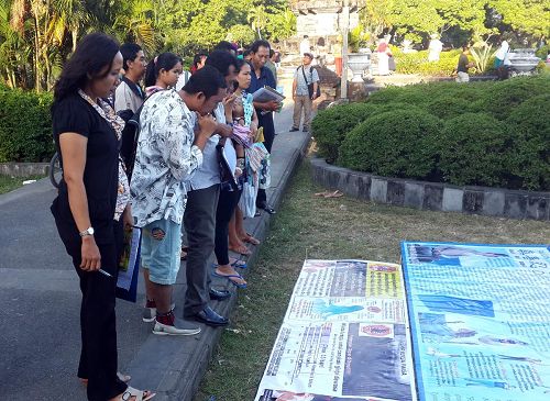 '巴厘岛登巴萨市Pupudan Badung公园里，人们认真阅读法轮功真相展板'