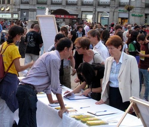 图5：二零一四年十月三日傍晚，在马德里市中心的太阳门广场，一位西班牙女士认真了解法轮功真相，并签名谴责中共活摘器官