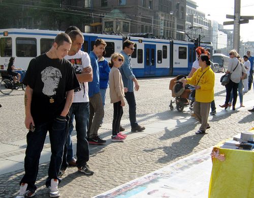 图：阿姆斯特丹的达姆广场上，游人认真了解法轮功真相