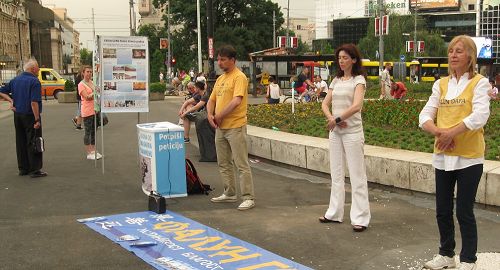 学员们在首都贝尔格莱德共和广场演示功法，民众看真相展板