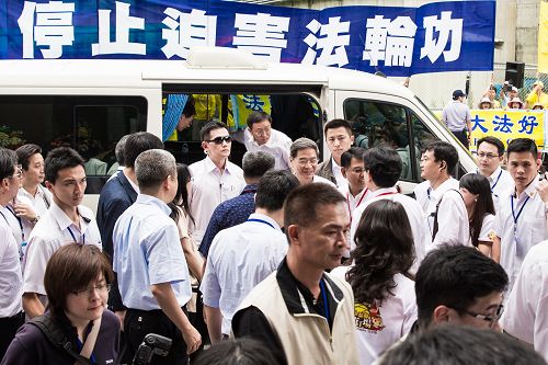 图7：中共国台办主任张志军等人在新北市五股区参访饼家，法轮功学员高举“停止迫害法轮功”横幅。