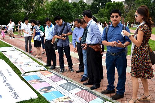 大批中、西方游客认真阅读讲述法轮功真相的展板和图片。