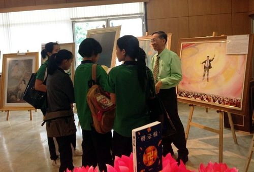 法轮功学员向前来参观的大学生介绍美展作品。