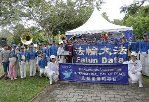 法轮功学员组成的天国乐团与联合国驻马来西亚协调员蜜雪儿（中间戴花者）开心合影