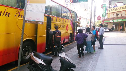 法轮功学员（中间穿紫色上衣，手拿资料者）给正在上车的大陆游客派发真相资料。