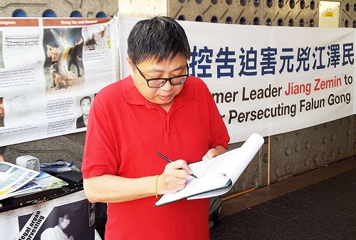 图1：帕拉马塔市议员约翰·胡正在签名声援中国法轮功学员控告迫害法轮功元凶江泽民