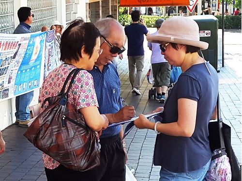 图：华人陈氏夫妇正在签名支持法轮功学员反迫害