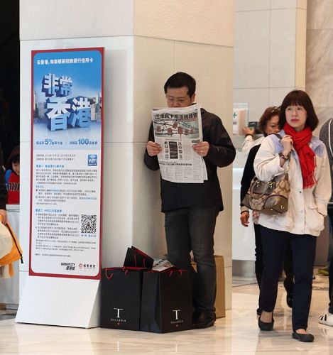 在尖沙咀闹市，大陆游客站着阅读揭露中共活摘器官的真相特刊。