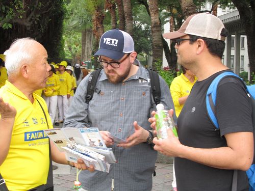 图6-10：中西游客及路人驻足拿取资料并聆听法轮功学员讲真相。