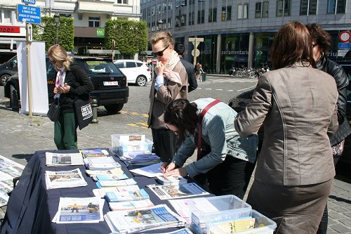 图1-3：在欧洲议会大厦前举办讲真相活动，很多民众在“反对活摘法轮功学员人体器官的征签簿”上签名