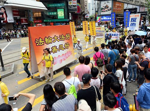 图5-10：法轮功学员的游行队伍在天团乐团引领下，走过港岛区闹市街道，吸引港民及中西游客驻足观看及拍照。