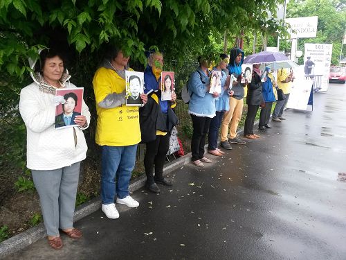 法轮功学员手持被迫害致死学员的照片在使馆前抗议