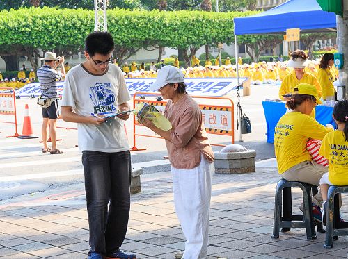 图9：学员（右）给过往的民众讲述江泽民迫害法轮功的真相，民众签名联署刑事举报江泽民。