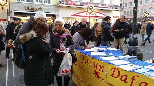 '图1~3:在当天的反迫害征签日活动中,各国游客和当地居民驻足了解真相并签名支持法轮功反迫害'