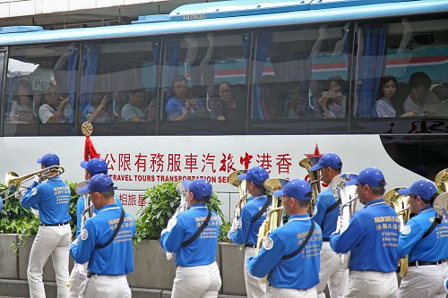 图9：公交车上乘客为法轮功的游行队伍所吸引，举起手机拍照。